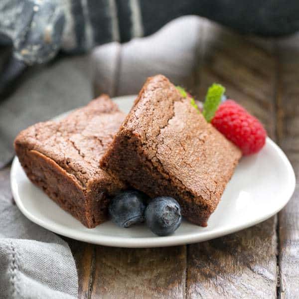 Simple Fudgy Brownies on an oval white dish garnished with fresh berries