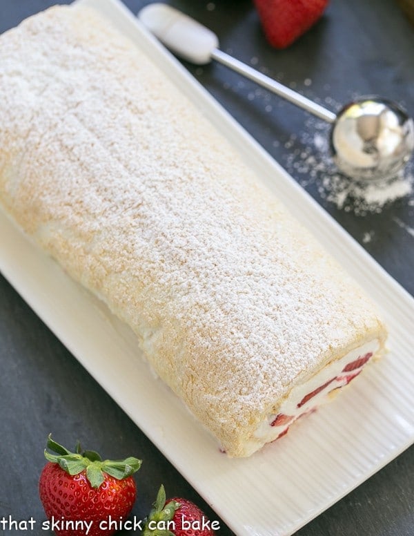 Strawberry Filled Meringue Roulade on a white ceramic serving tray
