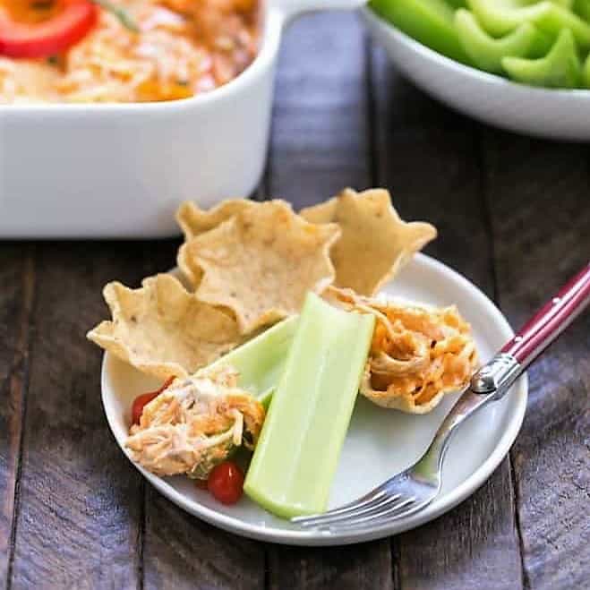 Buffalo Chicken Dip on a small appetizer plate with chips and celery.