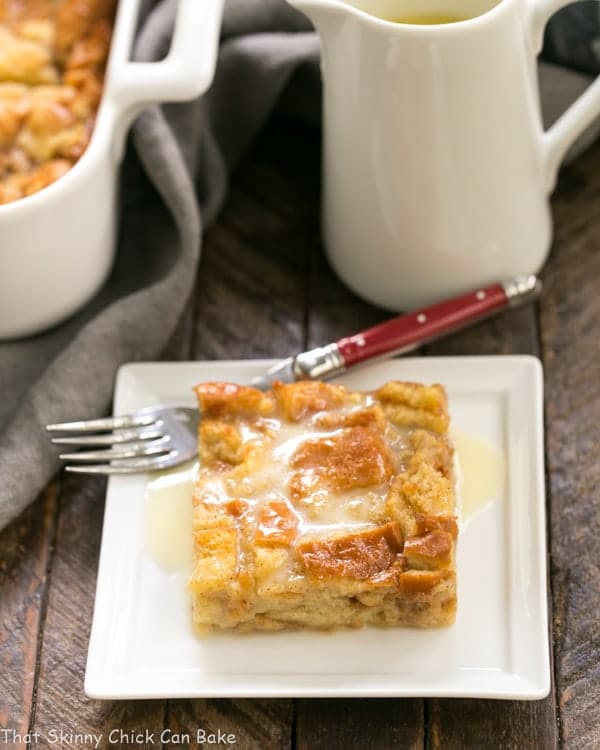 Slice of Cinnamon Bread Pudding with Whiskey Sauce on a square white plate.