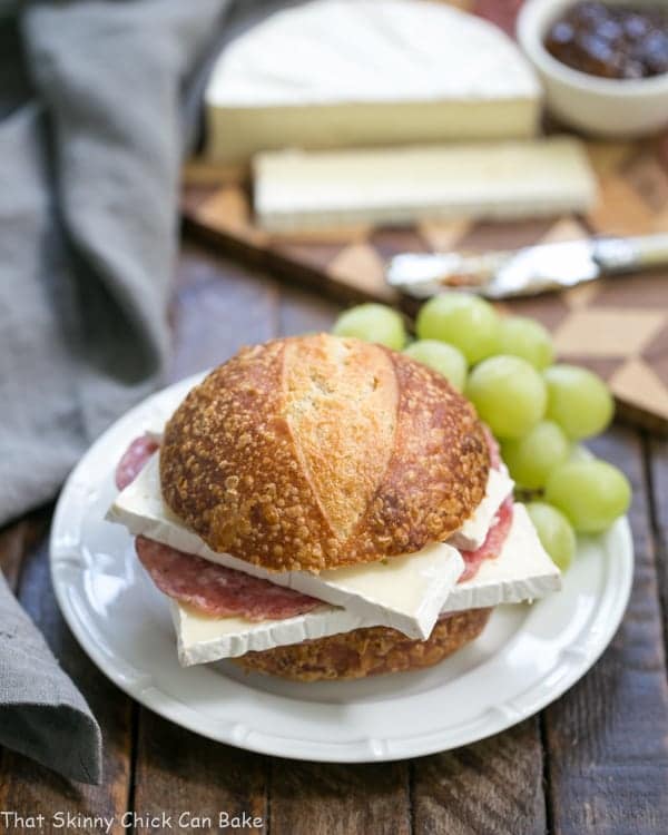 Brie Jam and Salami Sandwich on a white plate with green grapes.