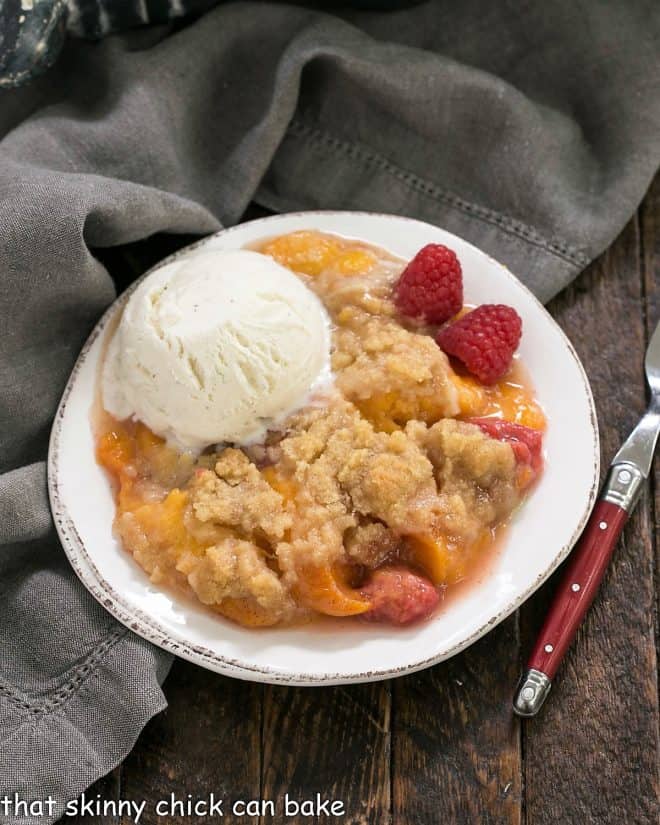 Overhead view of peach raspberry crisp topped with a scoop of ice cream