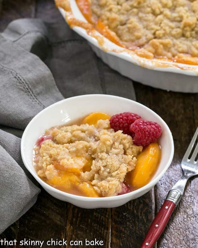 Peach raspberry crisp in a dessert bowl with a red handled fork
