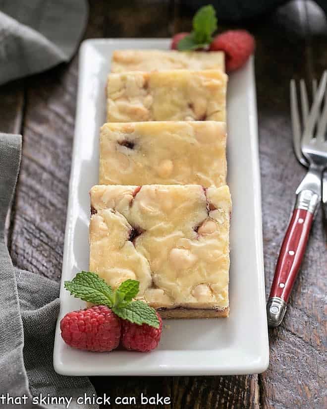 White Chocolate Raspberry Bars lined up on a rectangular white tray.