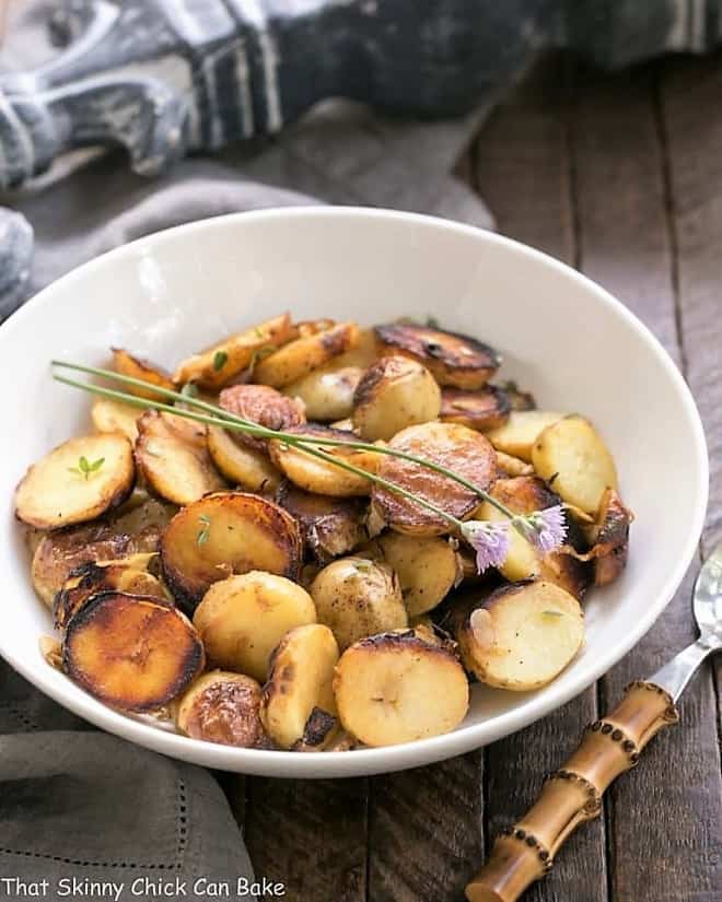 Grilled Potato Packets with Shallots and Thyme in a white serving bowl with a bamboo handled fork