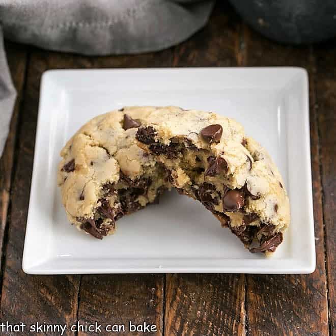 Levain Chocolate Chip Cookie broken in half on a square white plate.