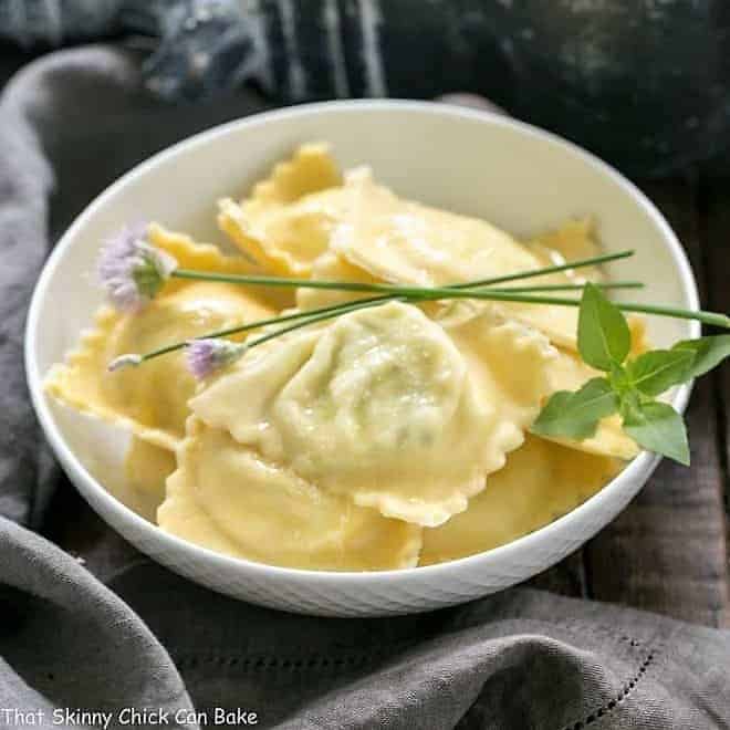 Bowl of Mozzarella, Basil, Parmigiano-Reggiano Ravioli with Butter Sage Sauce garnished with fresh basil and chives