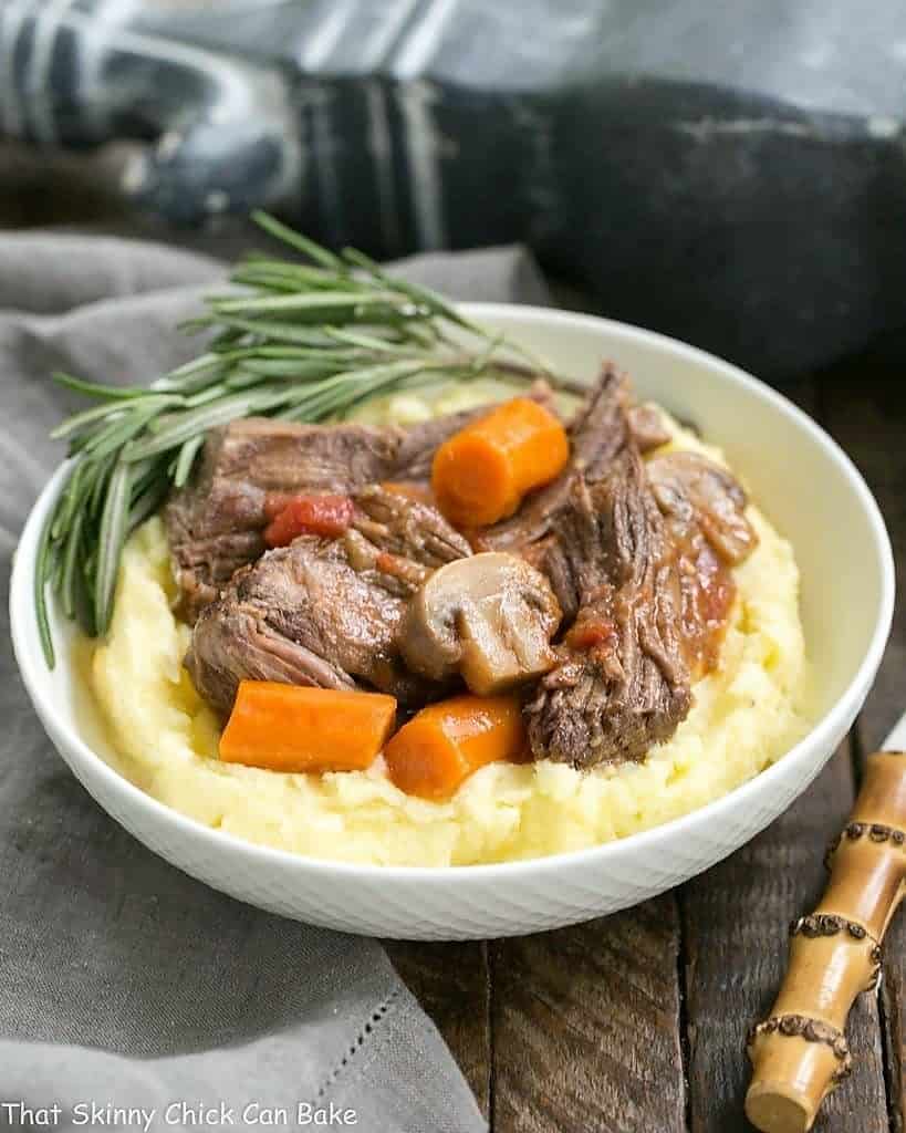 Pot Roast with Mushrooms, Tomatoes & Red Wine in a bowl with mashed potatoes.