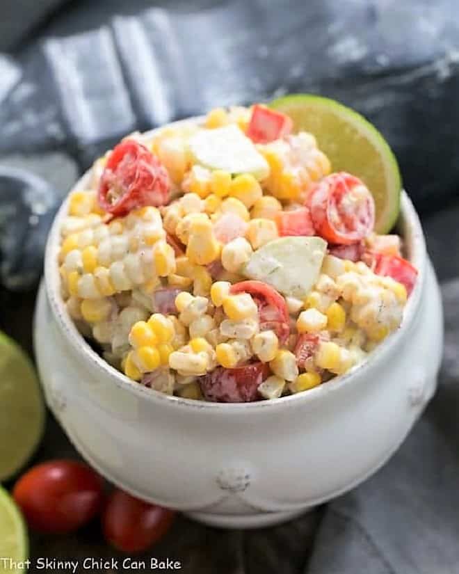 Spicy Mexican Street Corn Salad - Fresh sweet corn and veggies with a spicy mayo based dressing makes for an unrivaled summer corn salad! Spicy Mexican Corn Salad in a white bowl.
