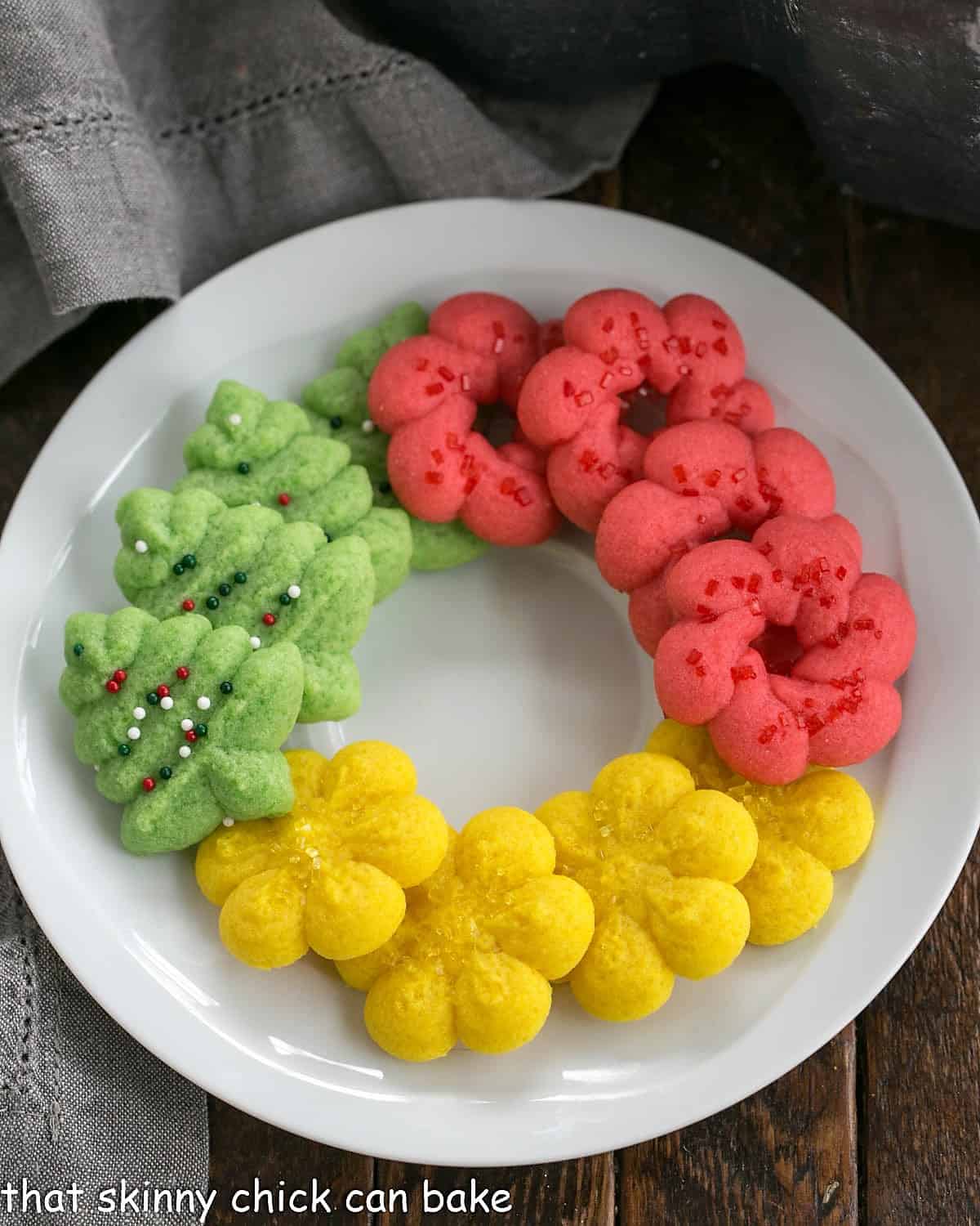 Overhead view of decorated spritz cookies on a round white plate.