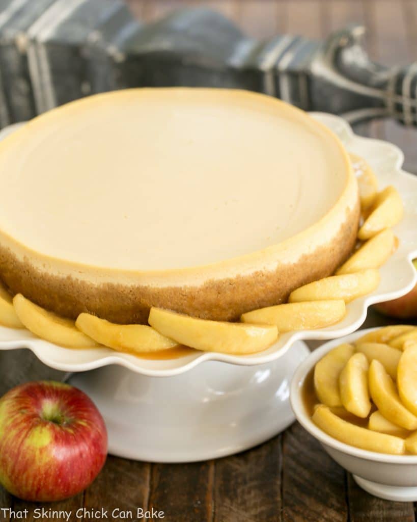 Easy Sour Cream Cheesecake with Caramel Apples on a white ceramic cake stand 