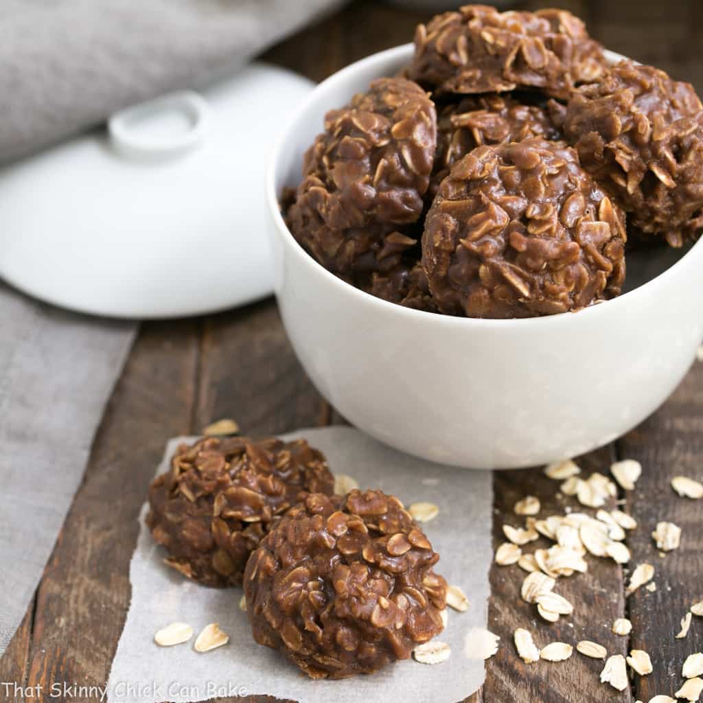 Classic Chocolate Peanut Butter No Bake Cookies in a white bowl with two cookies in the foreground.