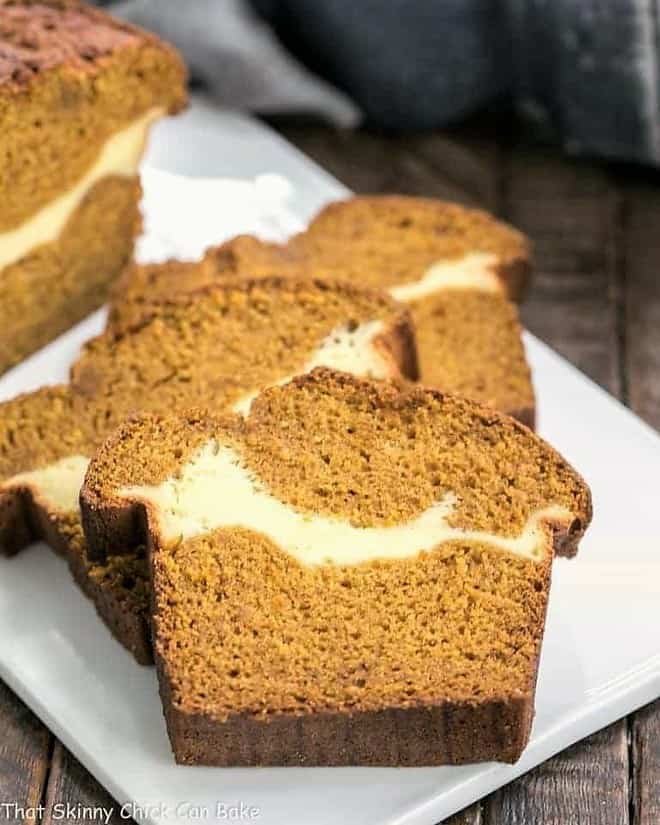 Cream Cheese Filled Pumpkin Bread A moist, delicious pumpkin loaf with a ribbon of cream cheese in the middle! Cream Cheese Filled Pumpkin Bread slices on a white platter.