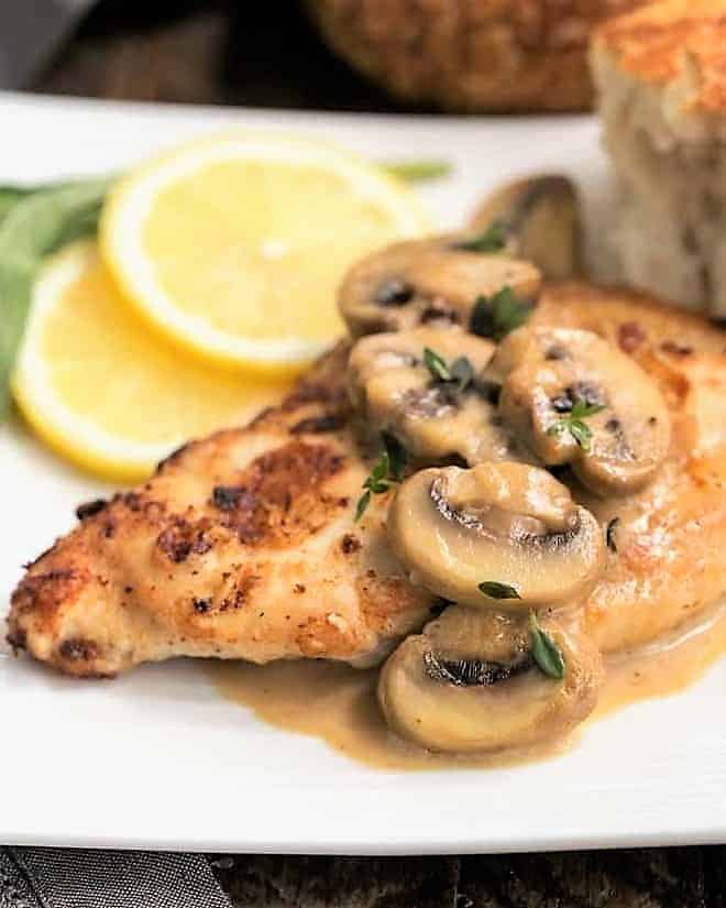 Creamy Chicken Marsala with Herbed Mushrooms on a dinner plate with lemon slices