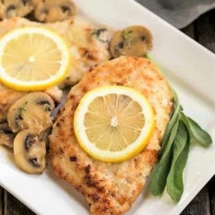 Creamy Chicken Marsala with Herbed Mushrooms topped with lemon slices on a white platter