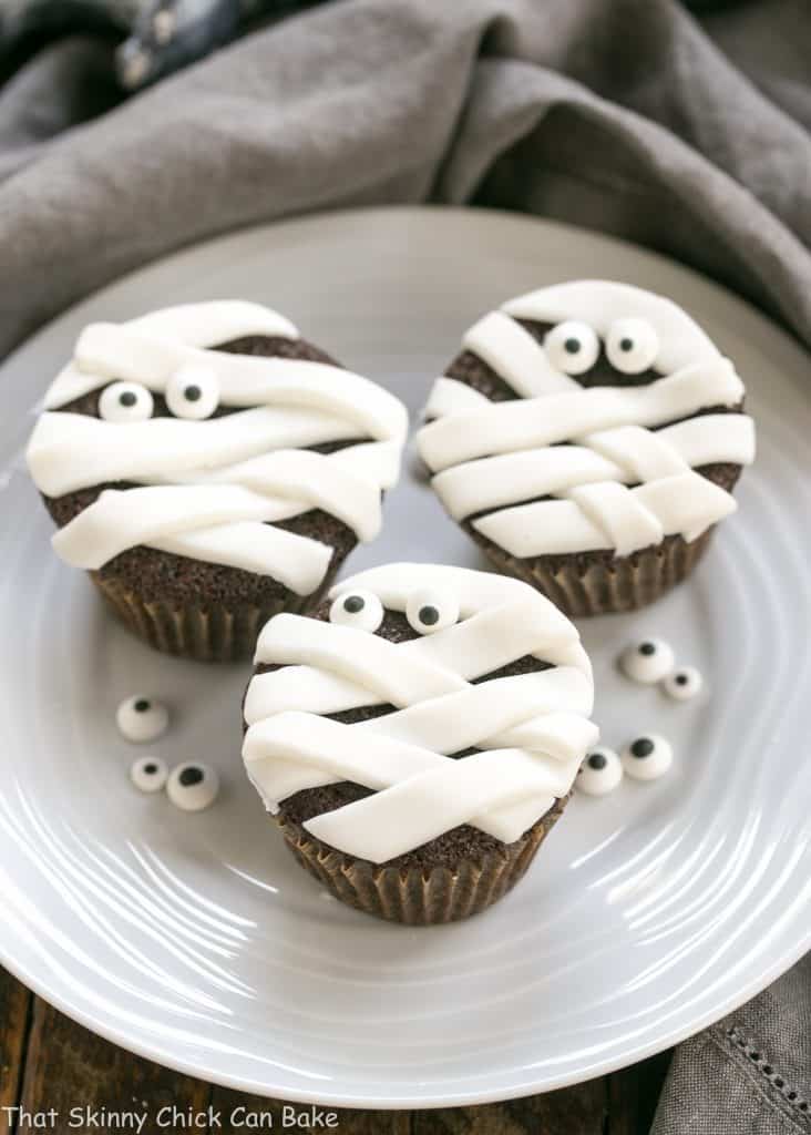EASY Chocolate Mummy Cupcakes on a round white ceramic plate garnished with sugar eyes
