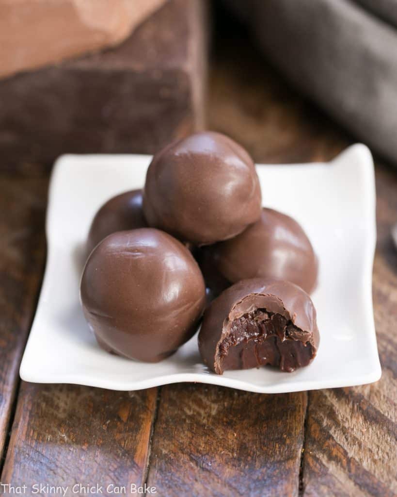 Chocolate Frangelico Truffles on a square white plate with one exposing the filling