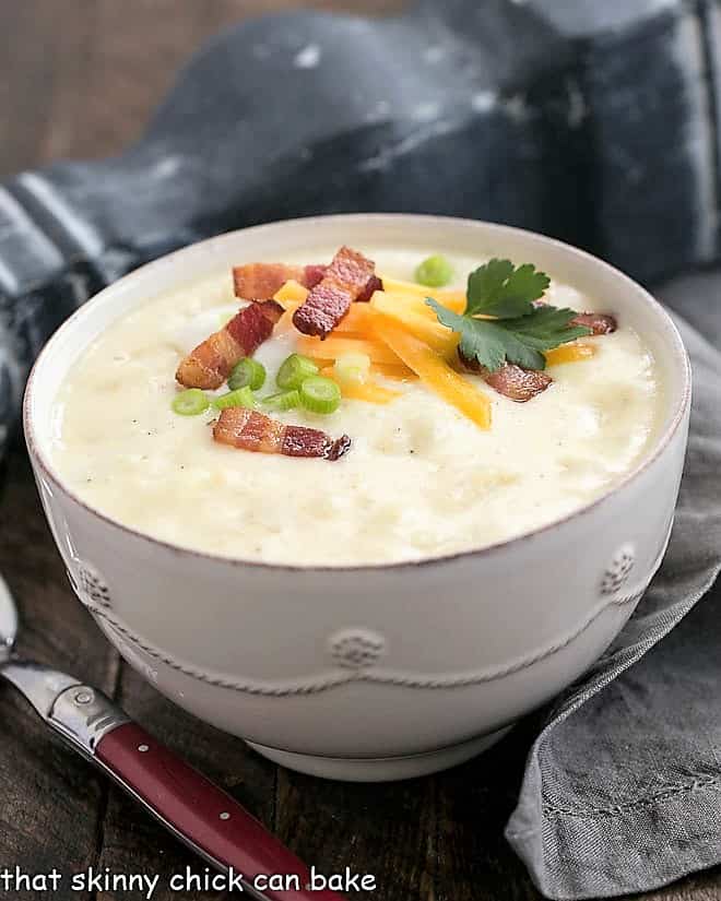 Loaded Baked Potato Soup in a white terrine garnished with cheese, bacon and chives.
