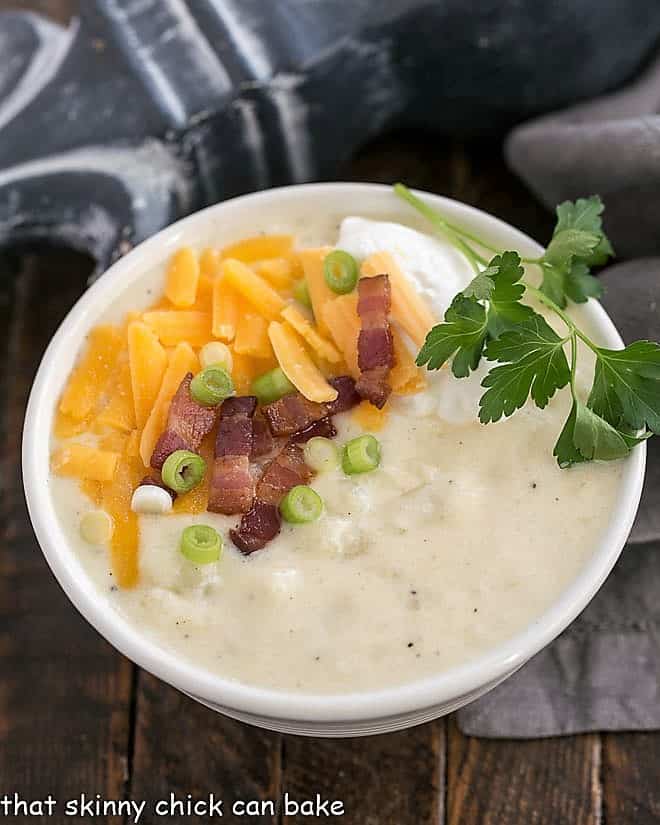 Loaded Baked Potato Soup in a white bowl with cheese and bacon garnish.