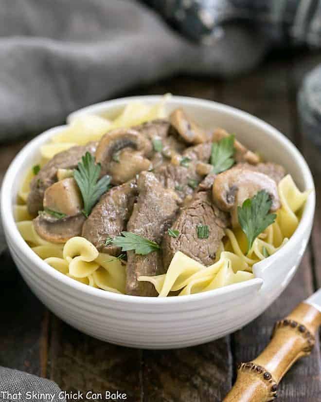 Easy Beef Stroganoff in a white bowl over buttered noodles.