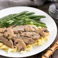 Easy beef stroganoff on a white plate with green beans