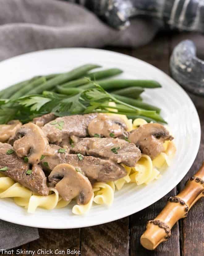 Easy beef stroganoff on a white plate with green beans