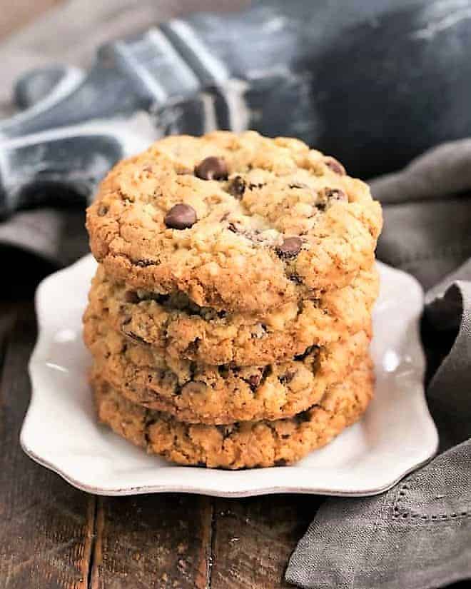 4 cowboy cookies stacked on a square white plate.