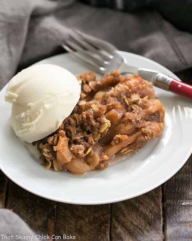 Easy Slow Cooker Apple Crisp with Oatmeal on a white dessert plate with a scoop of ice cream.