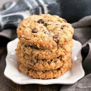 Loaded Cowboy Cookies stacked on a square white plate