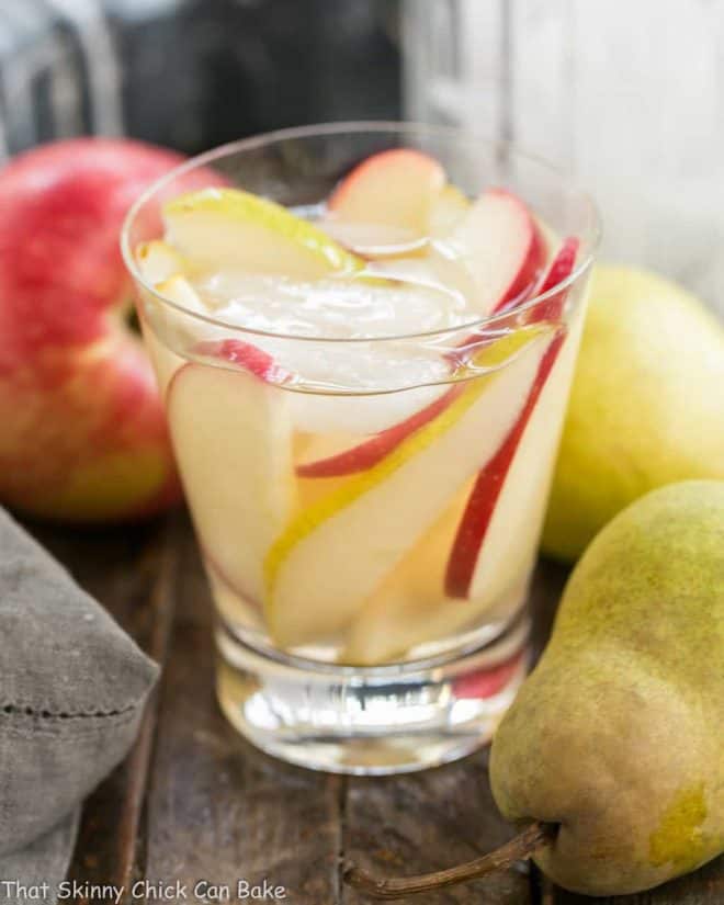 Apple Cider Sangria in a highball glass with ice, apple and pear slices