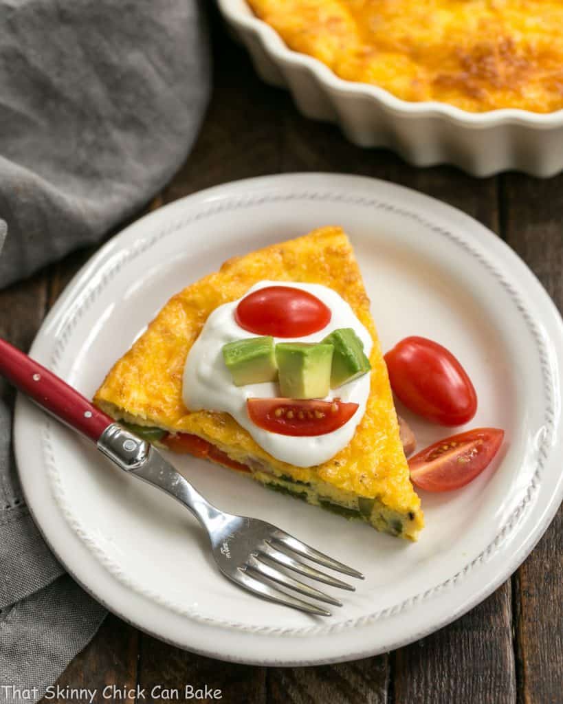 Baked Denver Omelet slice on a white plate with a red handled fork