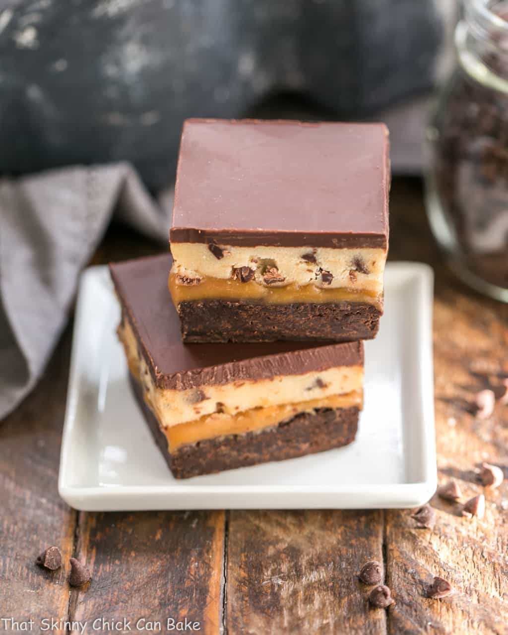 Cookie Dough Billionaire Bars stacked on a square white plate.