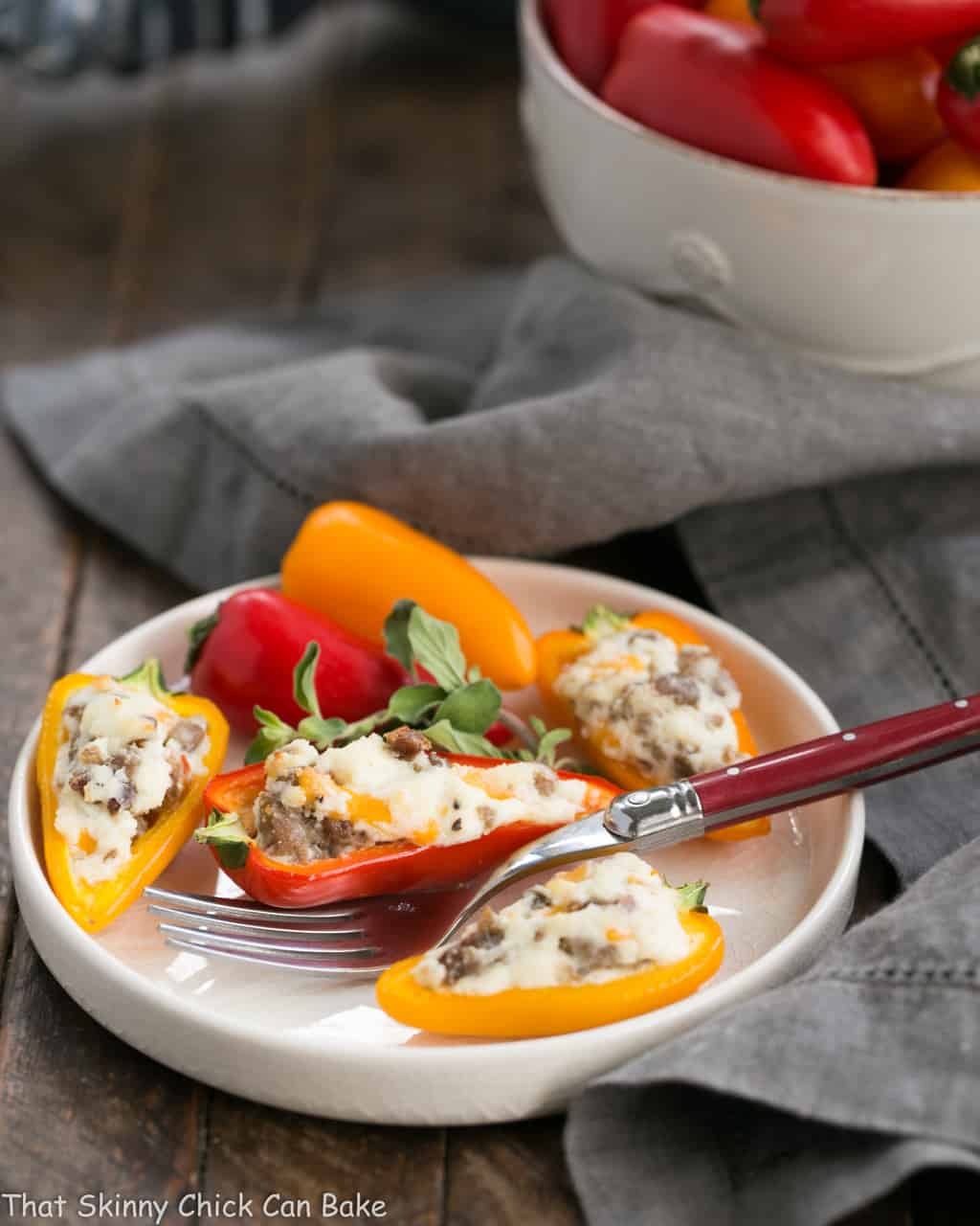 Cream Cheese Stuffed Mini Peppers with Sausage on a round white plate with a red handled fork.
