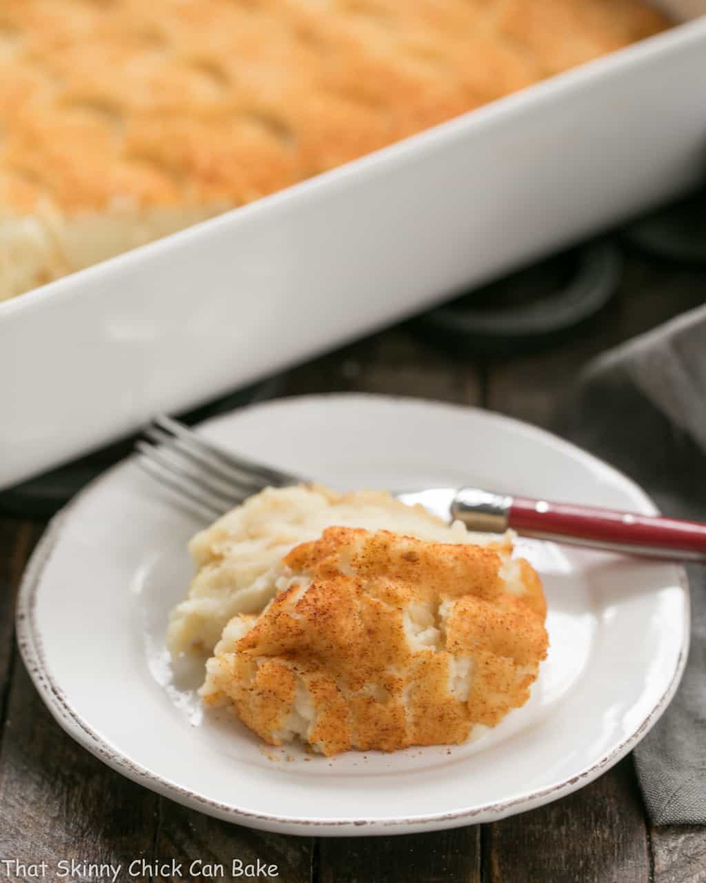 Easy Puffed Potatoes Casserole on a small white plate with a red handle fork.