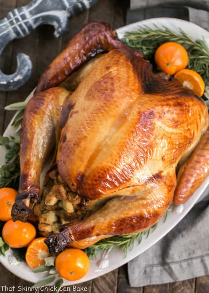 Honey Brined Turkey Recipe - The perfect way to get succulent meat from your holiday turkey Honey Brined Turkey on a white platter garnished with herbs and oranges