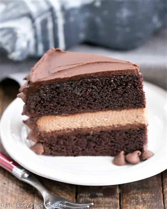 a slice of rich chocolate layer cake with a filing of milk chocolate cheesecake