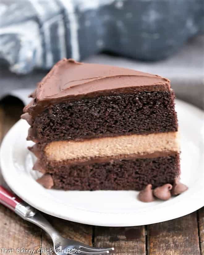 a slice of rich chocolate layer cake with a filing of milk chocolate cheesecake.