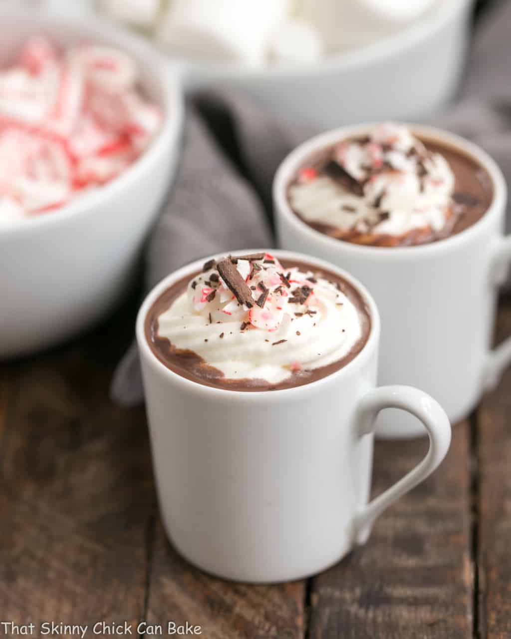 Two mugs of Easy Peppermint Hot Chocolate topped with whipped cream.
