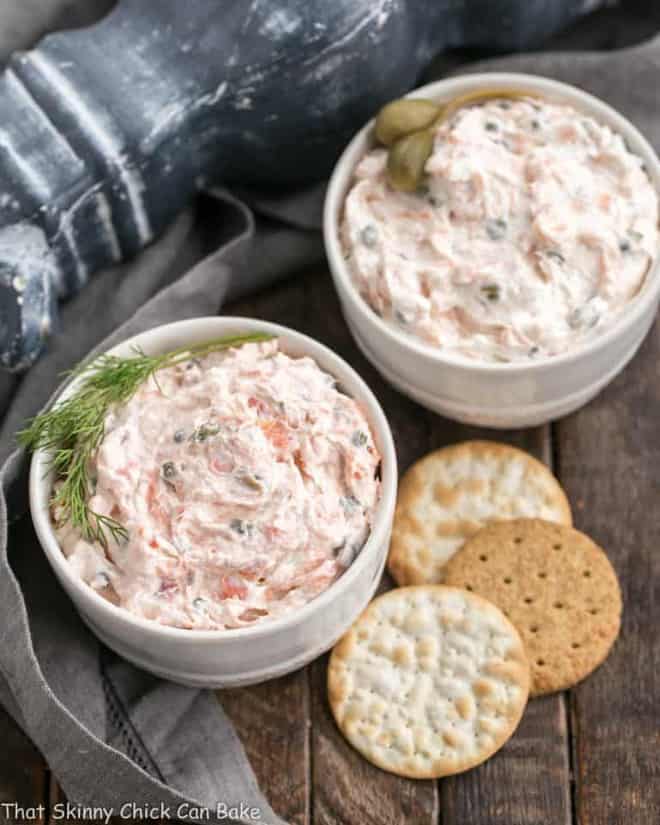 2 bowls of creamy smoked salmon dip with crackers on the side.
