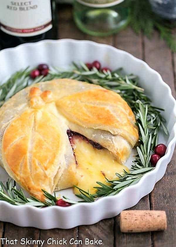 Cranberry Brie en Croute in a white ceramic dish garnished with rosemary and cranberries