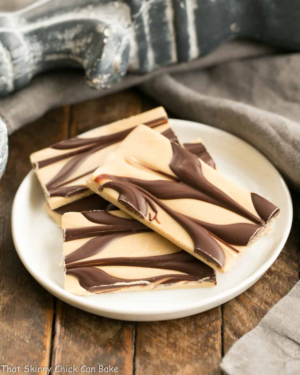 Four pieces of Peanut Butter Chocolate Tiger Bark on a small, round white plate.