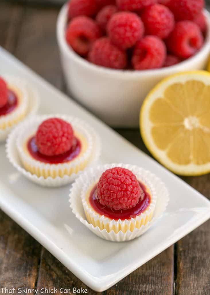 Raspberry Topped Mini Cheesecakes | Creamy mini cheesecakes topped with raspberry sauce and a plump ripe raspberry!