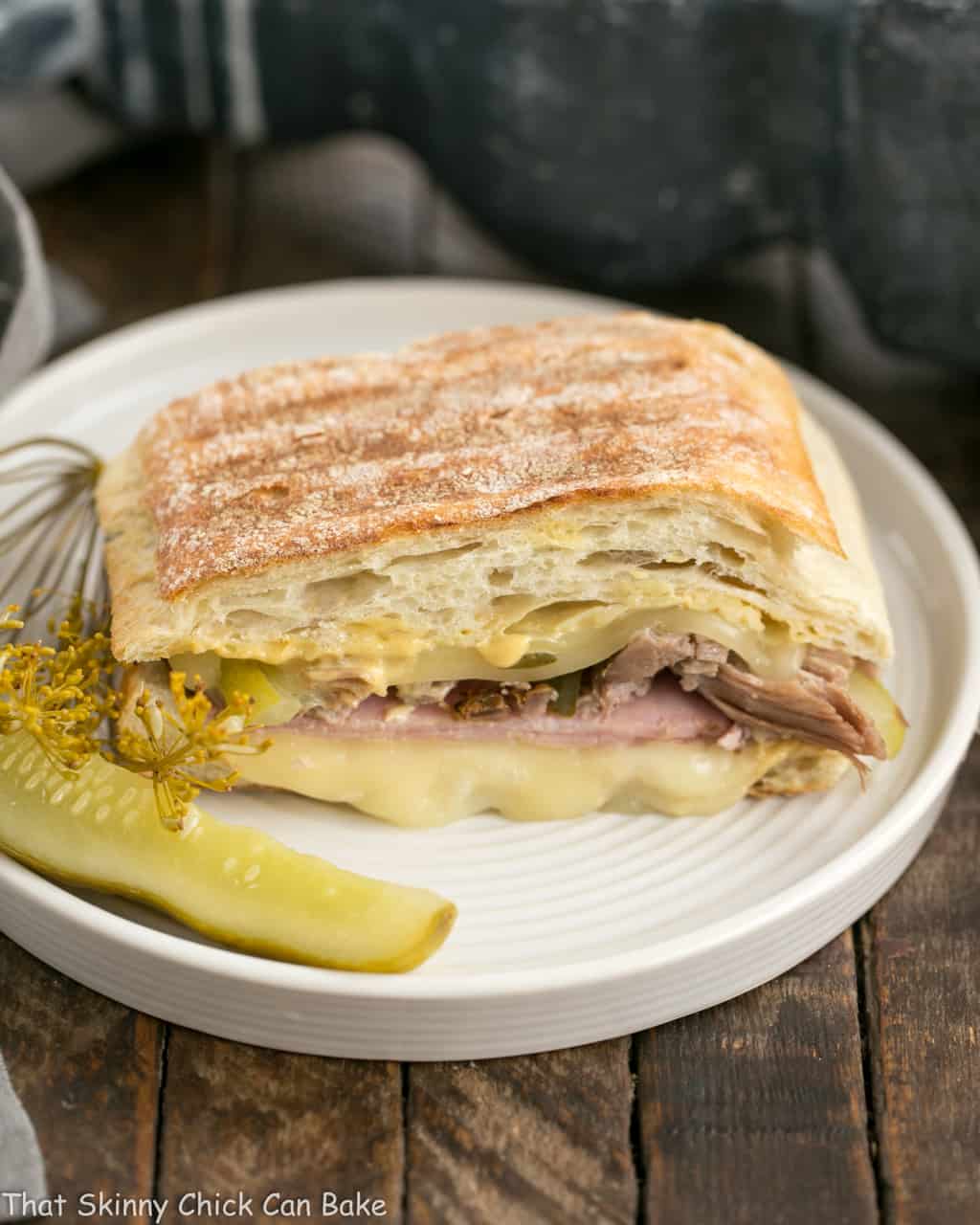 Ciabatta Cubano Sandwich Recipe on a round plate with a dill pickle.