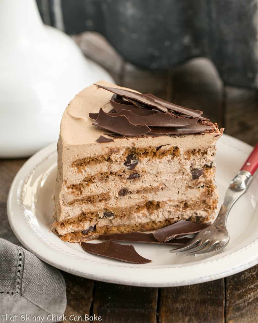 Mocha Chocolate Chip Cookie Icebox Cake slice on a white dessert plate with a red handled fork.