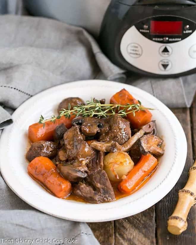 Slow cooker beef stew with mushrooms in a white soup bowl.