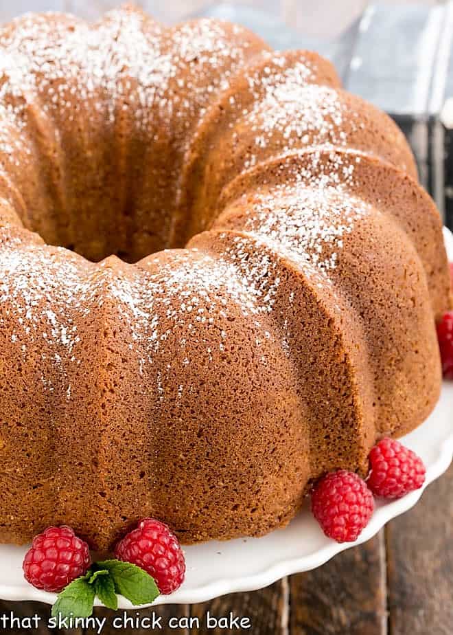 Close view of white chocolate Bundt Cake on a cake stand with raspberries and mint