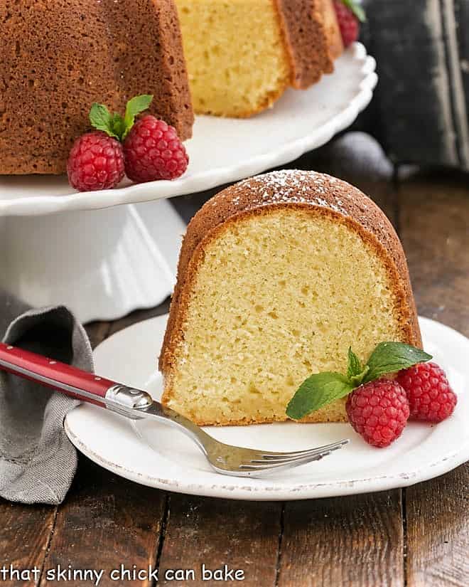 slice of white chocolate pound cake on a white plate with raspberries.