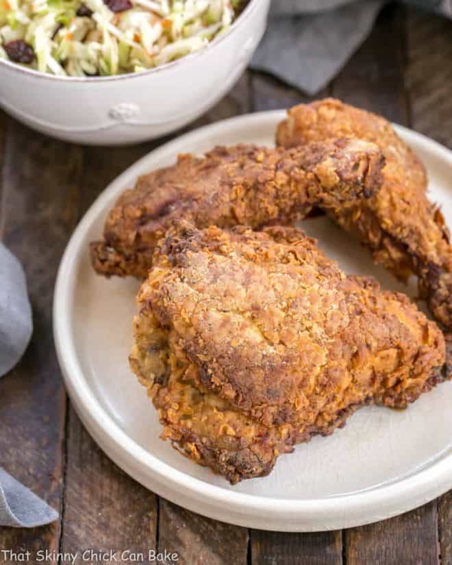 Easy Southern Fried Chicken on a white dinner plate with a bowl of coleslaw in the background