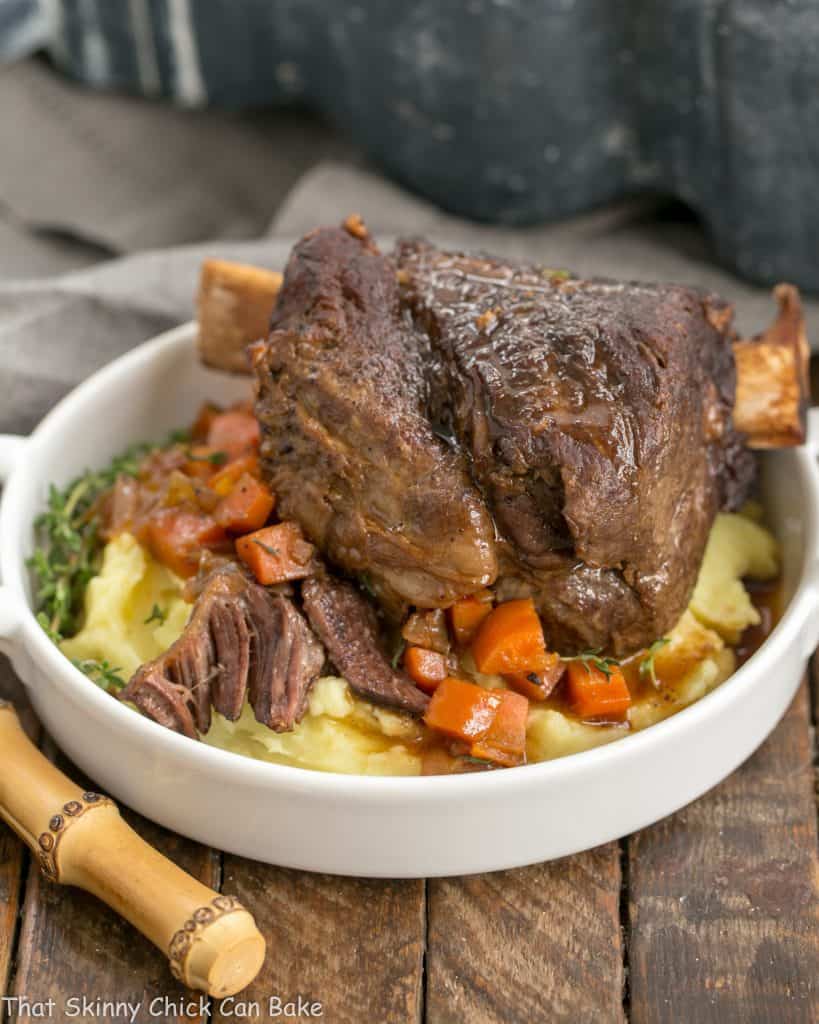 Instant Pot Beef Short Ribs on a round white plate over mashed potatoes and carrots
