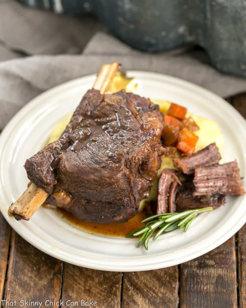 Instant Pot Beef Short Ribs on a round white plate garnished with rosemary